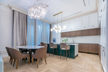 Bright and airy kitchen features a chic dining table paired with comfortable chairs. Elegant lighting enhances the modern decor, creating a welcoming atmosphere for gatherings.