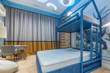 A bright bedroom features a blue bunk bed, modern desk, and colorful wall art. Soft curtains and stylish decor create a cheerful and inviting atmosphere.
