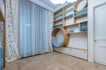 Bright children's room featuring a unique round chair, light curtains, wooden shelves, and a serene atmosphere, perfect for play and relaxation during the day.
