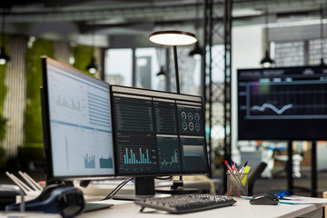 Empty corporate office features modern technology and dual monitors, analytics tools ready for...