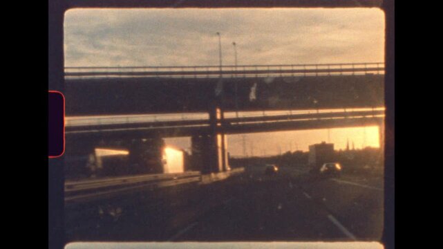 Sunset light glows through highway overpass during a nostalgic drive captured on vintage 8mm film with authentic analog film grain and soft focus