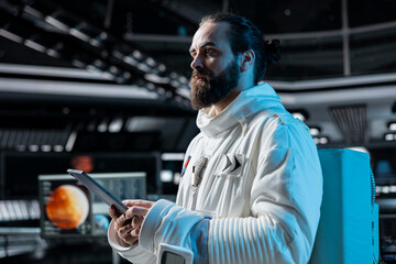Cosmonaut in orbital station looking at Mars data analysis interface on tablet. Man working on orbital station looking at galaxy visualization, doing Martian surface research to assist planetary