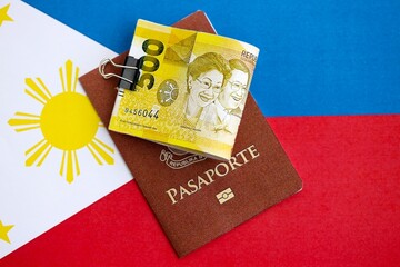 Philippines peso currency money bills and passport lies on flag close up. The concept of travel and...
