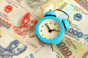 Vietnamese dong currency money bills and alarm clock close up. The concept of time management and...