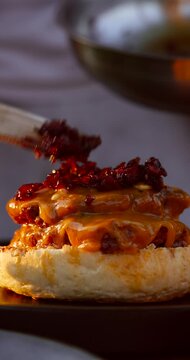 Close-up of juicy homemade burger being assembled on a sunny day. Grilled patty, sauce, bun, and fresh ingredients. Appetizing and natural 4k 60fps.