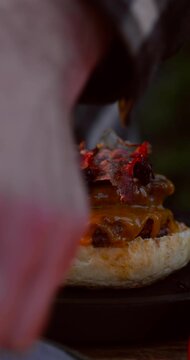 Appetizing homemade burger being assembled on grill under sunlight. Juicy patty bun melted cheese lifestyle food concept 4k 60fps.