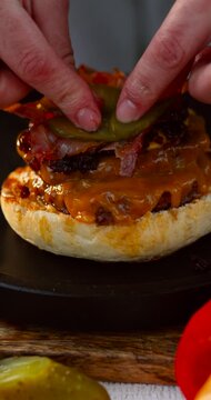 Vertical video of homemade grilled burger being assembled with sauce and fresh toppings on sunny day. Tasty juicy and appetizing 4k 60fps.