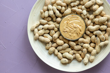 Close-Up of Peanuts on a Wooden Plate with a Bowl of Peanut Butter in the Center
