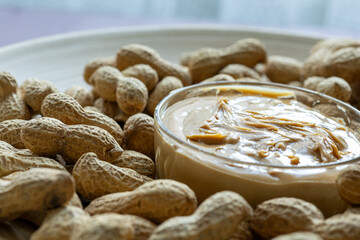 Close-Up of Peanuts on a Wooden Plate with a Bowl of Peanut Butter in the Center
