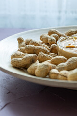 Close-Up of Peanuts on a Wooden Plate with a Bowl of Peanut Butter in the Center
