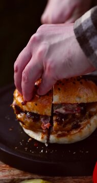 Vertical macro video of juicy burger cut in half showing melted cheese and meat inside. Appetizing closeup 4k