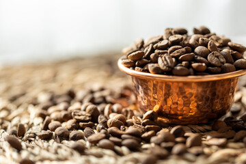 Fototapeta premium Close-Up of Coffee Beans in a Copper Mini Cup on a Brown Textured Surface 