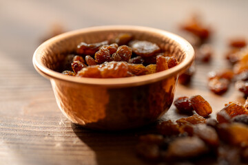 Dried Raisins in a Copper Bowl on a Brown Wooden Table
