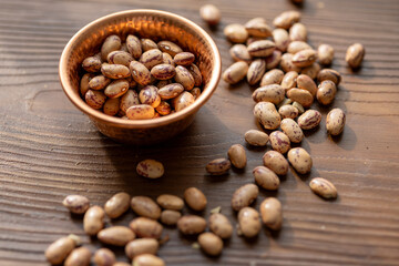 Close-Up of Borlotti Beans in a Copper Bowl on a Brown Background Under Sunlight
