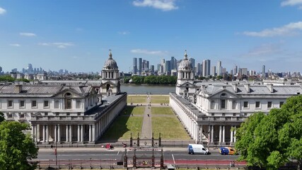 Drone footage showing historic riverside architecture with modern skyscrapers across the river, blending heritage, innovation, and urban skyline under a clear blue sky.
