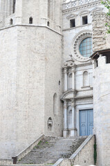 Fototapeta premium Historic stone building with a cylindrical tower, arched windows, and a grand entrance with blue double doors and ornate carvings, set in a scenic European town.