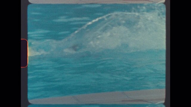 Young brother gleefully lifts his little sister overhead before hurling her into the turquoise pool with exuberant splashes unfolding in nostalgic slow motion under sunny skies, capturing joyful