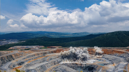 Dynamic open pit gold ore mining operations with explosive detonation in vast landscape