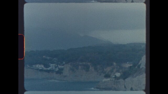 Hazy view of seaside cliffs and distant mountains captured on analog super 8 film with nostalgic film grain and soft focus