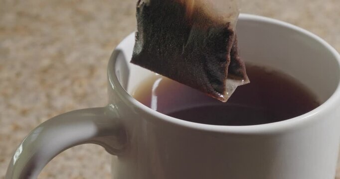 Close up of a tea bag spinning over a brewed cup in slow motion 