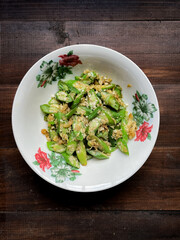 Home-cooked stir-fried okra with scrambled eggs served in a floral-rimmed white bowl on a dark wooden surface
