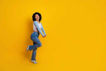 Cheerful young woman posing joyfully on yellow background showcasing vibrant casual fashion and uplifting positivity