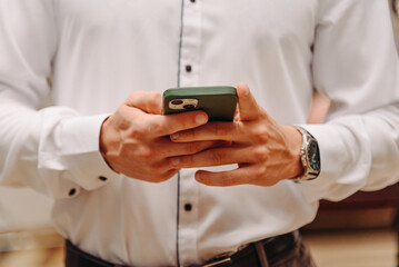 smartphone in hands, young man in white shirt, close-up view of hands, texting messages concept