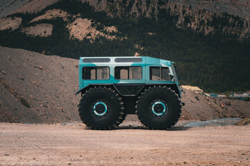 Obraz premium Off-road vehicle with oversized tires parked in mountain landscape.