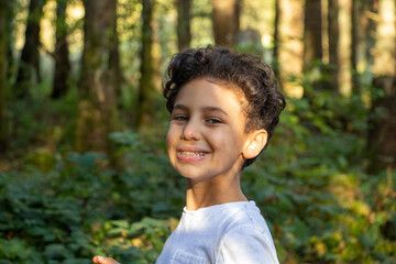 8 years old boy close up picture in the nature for a hiking and smiling with the power of nature.