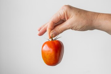 A hand holding a tomato