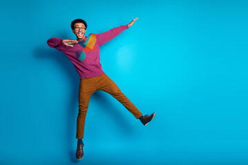 Obraz premium Trendy young man in vibrant sweater posing joyfully with unique style against bright blue background