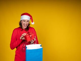 Woman opening excited christmas gift on yellow