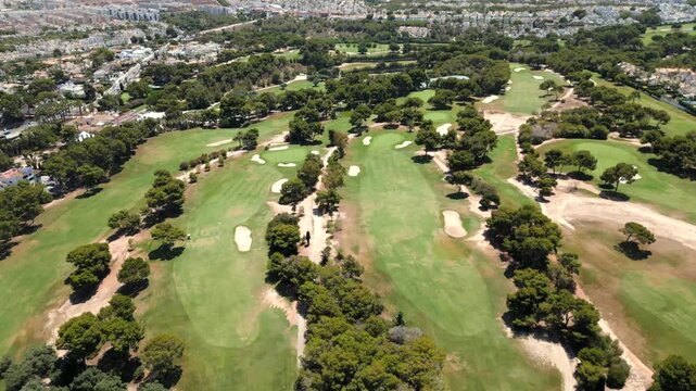 Aerial drone footage of La Zenia golf course in Orihuela Costa, Alicante, Spain. The
camera rises from the green landscape of the golf field to reveal the Mediterranean Sea
and urban skvline
