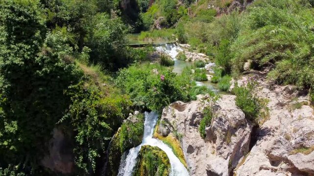 Aerial lateral drone footage of water dropping at the base of Gorgo de la Escalera
waterfall in Anna, Alicante, Spain. Scenic natural movement of falling water, rocks and
spray, ideal for travel, tour