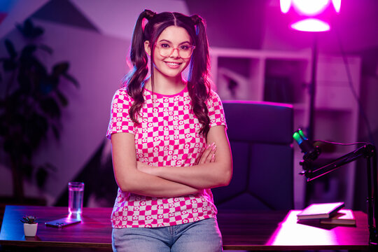 Adorable female content creator in a stylish casual outfit hosting an online broadcast from her personalized workspace.