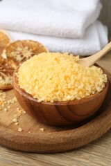 Natural sea salt with dried orange slices and towel on wooden table, closeup