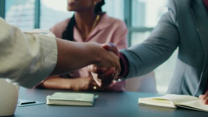 Closeup of business people shaking hands over meeting table in boardroom at office - Powered by Adobe