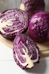 Obraz premium Whole and cut fresh red cabbages on white wooden table, closeup