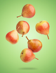 Many fresh pears falling on green background