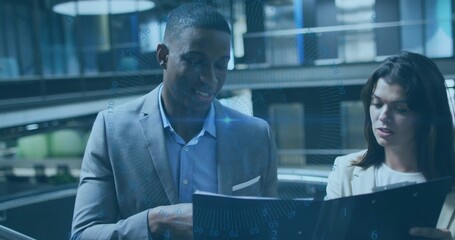 Reviewing documents colleagues leaning over open black binder in office atrium, data overlay