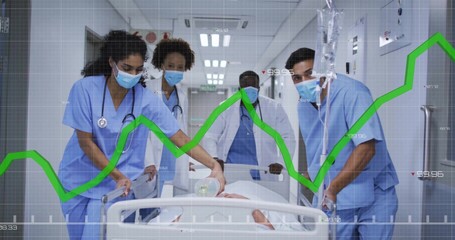 Moving scrub-clad team pushing patient on stretcher through hospital corridor, with bag valve mask