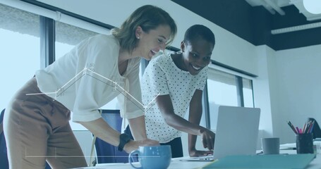 Collaborating colleagues pointing and typing on laptop in office with mugs and documents