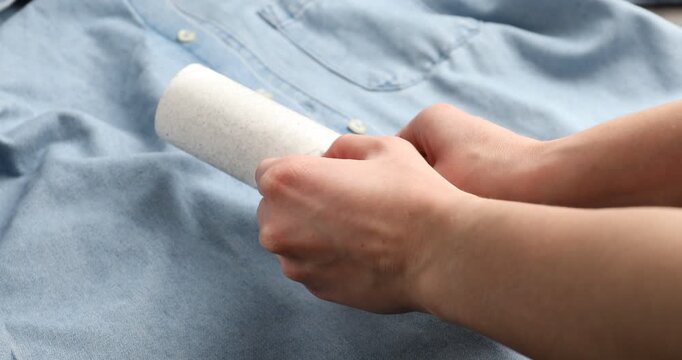 Woman cleaning shirt with lint roller, closeup