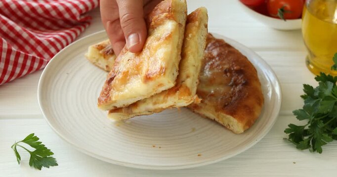 Woman taking pieces of delicious Megrelian khachapuri at white wooden table, closeup