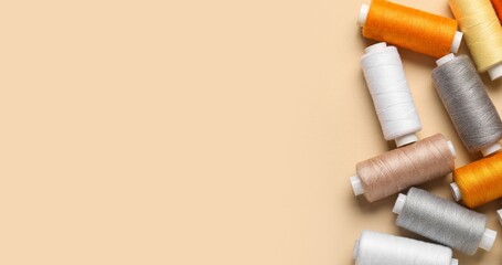 Many threads on beige background with space for text, top view