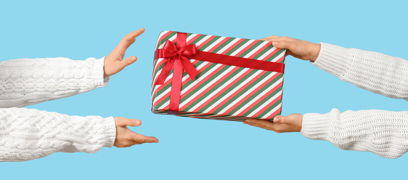 Female hands passing Christmas gift on blue background