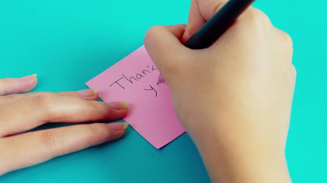 Hand writting 'thank you' with pen isolated on blue background 