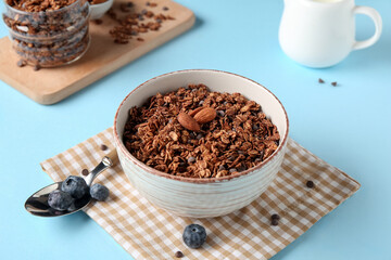 Bowl with tasty chocolate granola on blue background
