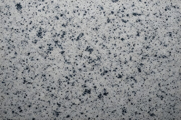 High-contrast abstract texture background with a fine-grain grey and white base, heavily covered in scattered clusters of dark blue-black speckles, resembling fine granite, cosmic dust, or sea foam.