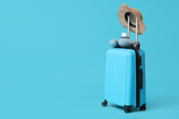 Suitcase with travelling belongings and camera on blue background